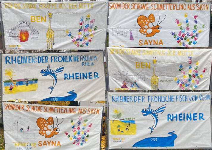 Die Banner zeigen die Symbolfiguren Ben, Rheiner und Sayna und Wahrzeichen der Stadt.