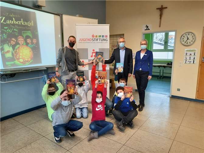 Die Drittklässler aus der Grundschule in Bad Neuenahr freuen sich sichtlich über das Buch „Im Zeichen der Zauberkugel – Das Abenteuer beginnt“ sowie die Lesung des Autors Stefan Gemmel. Quelle: Kreissparkasse Ahrweiler