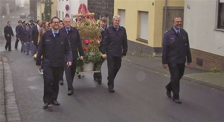 Die Feuerwehrleute des Eicher Löschzuges tragen die Erntekrone vom Feuerwehrhaus zur Kirche.privat