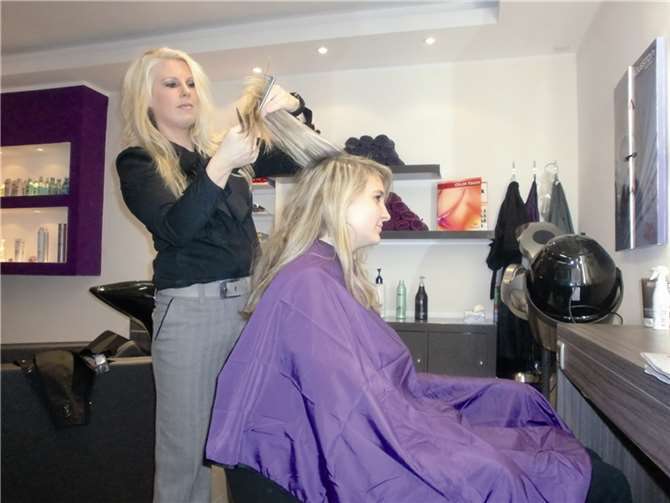 Die Friseurmeisterin beim Haarelegen einer Kundin in ihrem neuen Geschäft. privat