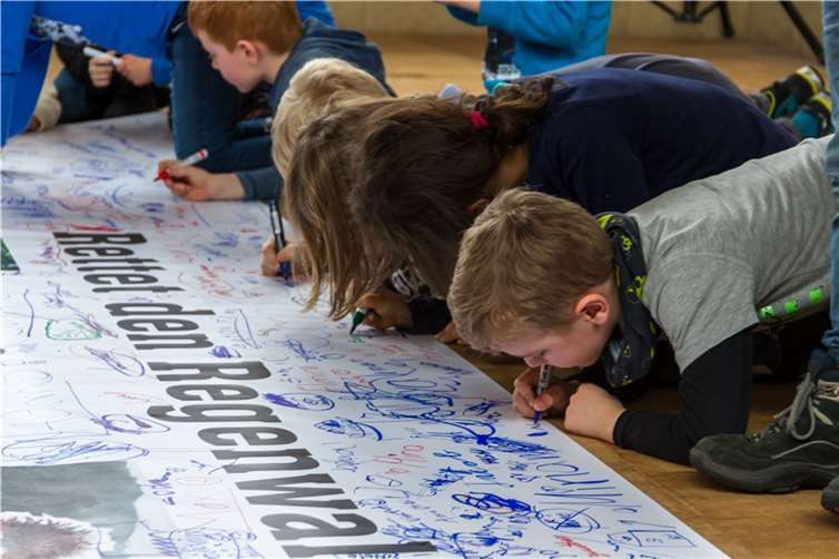 Die Kinder bekunden ihre Solidarität für Henrys Mission mit ihrer Unterschrift auf dem mitgebrachten Transparent. .Florian Over, Bennis Bruder