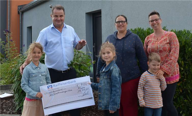 Die Kinder des Waldorfkindergarten Pusteblume mit Leiterin und Vorstand bekommen von Franz Wolber, Regionalmarktleiter Grafschaft der Raiffeisenbank Voreifel eG den Scheck überreicht. Foto: privat