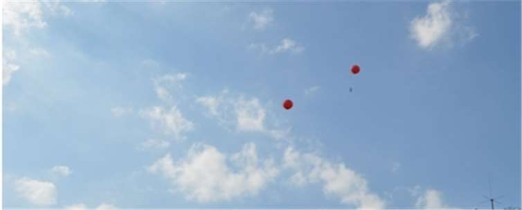 Die Kinder warten gespannt, wessen Luftballon am weitesten fliegt.