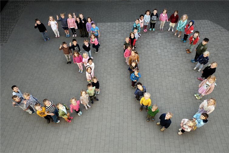 Die Kindergartenkinder formen eine 30 im Innenhof des Kindergartens.