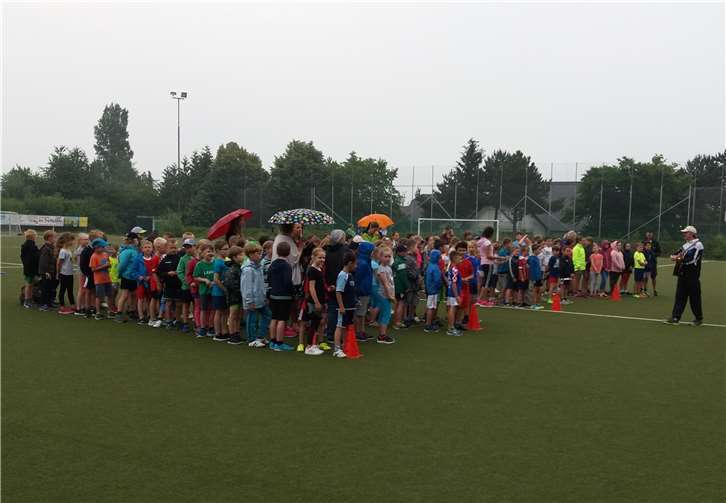 Die Klassenweise angetretenen Schüler vor dem Wettkampf mit ihrem Sportlehrer, Herrn Kohlhage, beim Singen des Sportfest Eröffnung Liedes. Große Runde nach dem Wettkampf beim Singen mit der Schulleiterin Frau Jaax und Herrn Kohlhage.privat