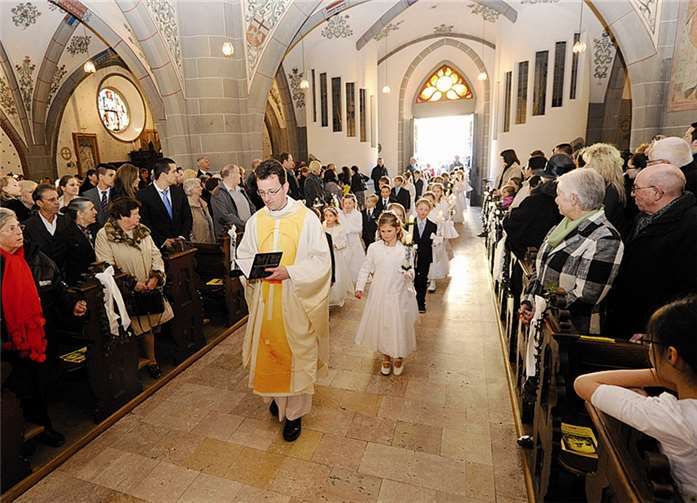 Die Kommunionkinder der Pfarrgemeinde St. Laurentius ziehen hinter Kaplan Andreas Kern in die Kirche ein. -FIX-