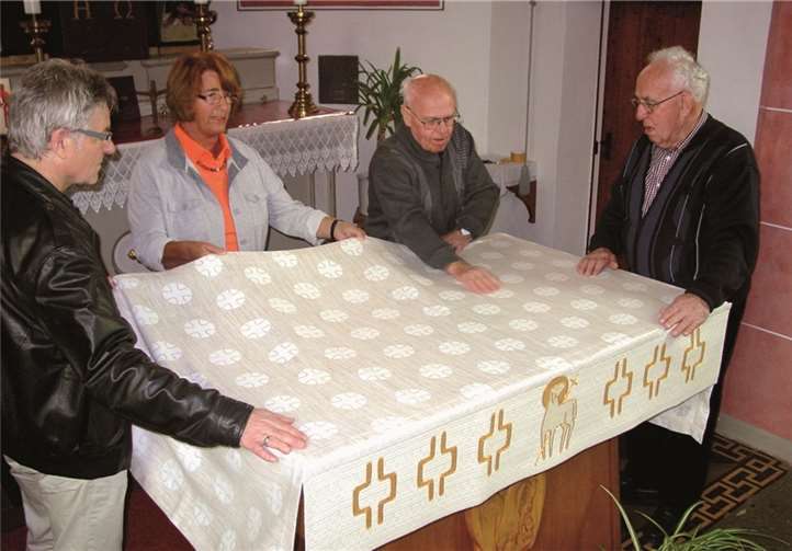 Die Küster der Dedenbacher Kapelle, Toni und Peter Weidenbach (re), legen zum ersten Mal die neue Decke auf den Altartisch. Mit ihnen freuen sich Roswitha Wihl vom Organisationsteam der weihnachtlichen Musik und Reinhold Hergarten, Mitglied des Verwaltungsrates der katholischen Pfarreigemeinde St. Nikolaus in Königsfeld. privat