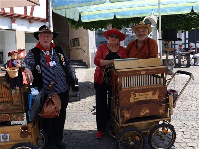 Die Menschen scharren sich um die Drehorgelspieler und Spielerinnen mit ihren Instrumenten. Sie singen die Lieder mit und genießen das schöne Wetter. Foto: JS