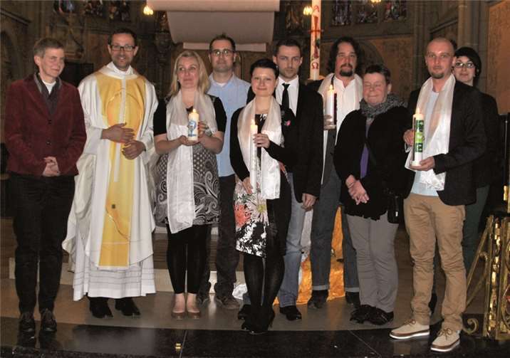 Die Neugetauften mit den Taufkerzen in den Händen und den Partnerinnen und Partner, die zugleich auch ihre Paten sind. privat