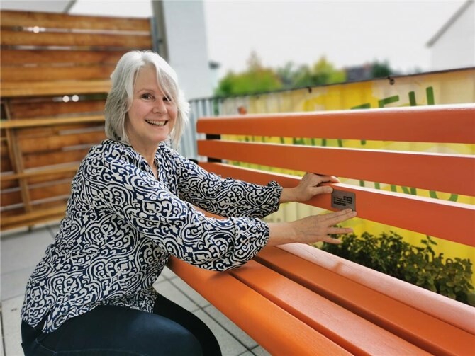 Die Neuwieder Gleichstellungsbeauftragte Birgit Bayer legt letzte Hand an die Orange Bank an. Die angebrachte Plakette informiert über das Hilfetelefon „Gewalt gegen Frauen“.  Foto: Alexandra Heinz