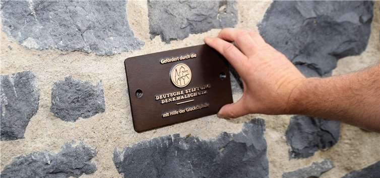 Die Plakette wird an der sanierten Mauer angebracht.