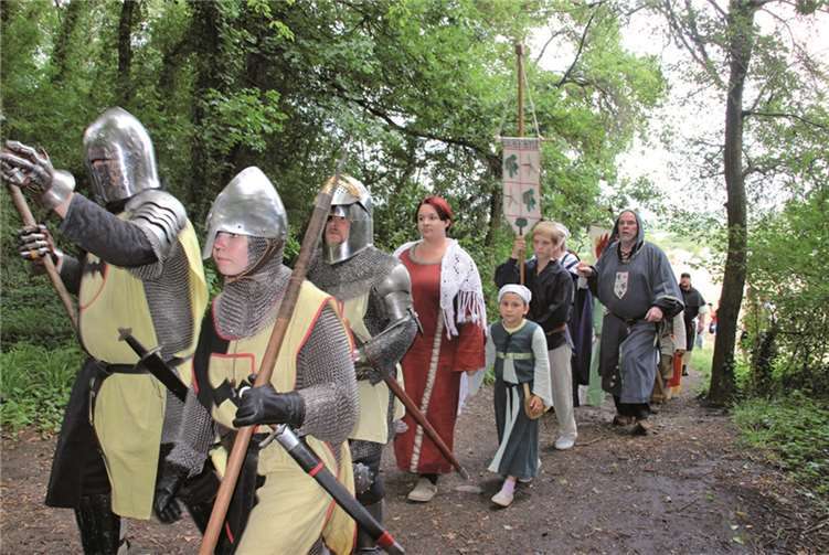 Die Ritter in voller Ausrüstung und ihr Gefolge schreiten auf den Waldplatz am Fuße der Tomburg. STEIN