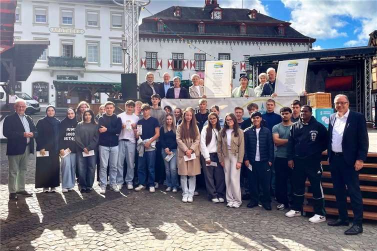 Die Schüler der Robert-Koch-Schule vor dem Start der Stadtrallye zusammen mit Stadtbürgermeister Helmut Muthers (rechts), dem Sprecher der Fair Trade Steuerungs-gruppe Hans-Joachim Schmitz (links) und auf der Bühne mit Mitgliedern der Fair Trade Steuerungsgruppe und des Weltladens.Foto: Caroline Fritzen, Tourist-Information Linz