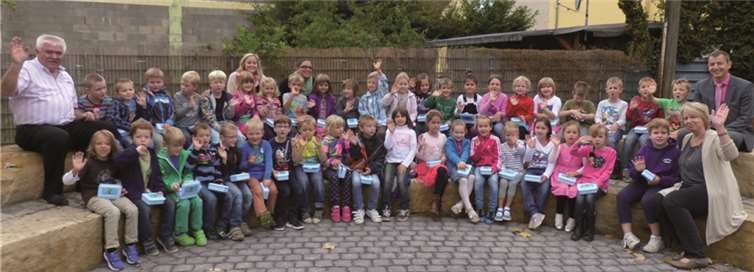 Die Schüler der ersten Klassen freuen sich mit ihrer Klassenlehrerinnen Anke Hoffmann und Susanne Spies über Frühstücksdosen, die ihnen von RWE-Kommunalbetreuer Michael Dötsch, Leiter der Region Rauschermühle (rechts) und Bernd Theisen, Fachbereichsleiter Schulen von der Verbandsgemeinde Pellenz, überreicht wurden.  Privat