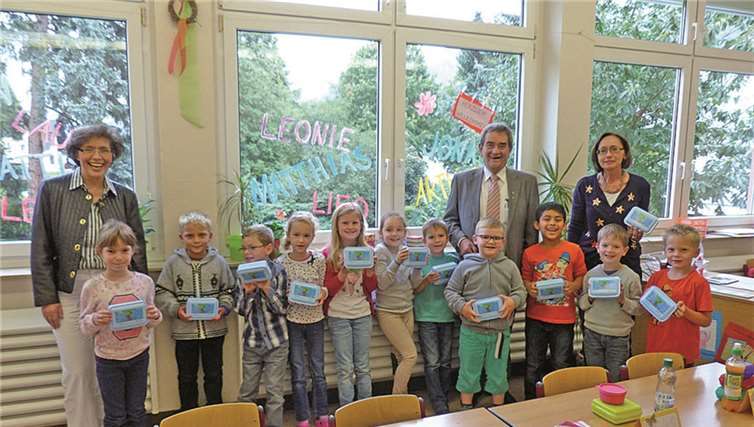 Die Schülerinnen und Schüler der ersten Klasse der Petrus-Mosellanus-Grundschule in Bruttig-Fankel freuen sich mit ihrer Klassenlehrerin Monika Neunheuser-Etzkorn über die Frühstücksdosen, die ihnen RWE-Kommunalbetreuerin Beatrix Ziegler gemeinsam mit dem Bürgermeister der Verbandsgemeinde Cochem, Helmut Probst, überreichte.