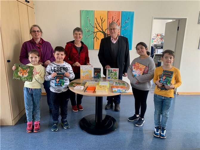 Die Schulleiterin Diana Pretz und die ukrainischen Kinder freuen sich zusammen mit der zuständigen Lehrerin über die Buchspende.  Foto: Pro Mendig