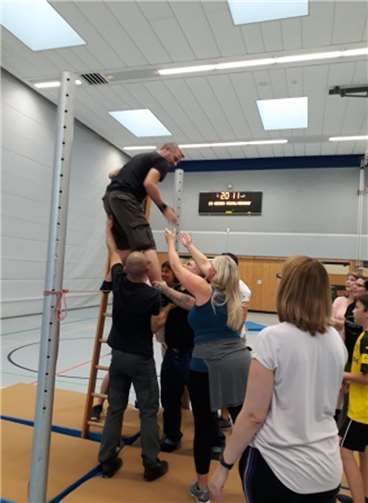 Die Sprossenwand muss von allen Mitgliedern überwunden werden, ohne sie zu berühren. Einziges Hilfsmittel ist eine Leiter.