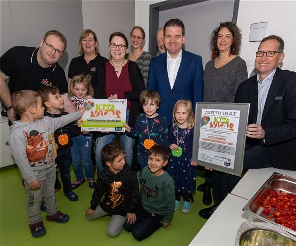 Die Vertreter von Stadt, Jugendamt, Gesundheitsamt, dem zertifizierenden Verein kivi e.V. und die Kinder zeigen ihre Urkunde und das Schild für die „Kita Vital“. Foto: CEW