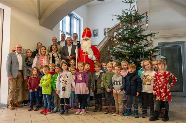 Die Vorschulkinder aus Melsbach, begleitet von Kita-Leiterin Annika Wolff und Team, brachten Weihnachtliche Stimmung in die Neuwieder Kreisverwaltung. Büroleiterin Diana Wonka, Landrat Achim Hallerbach, Sebastian Grobbel (Forstrevierleiter Straßenhaus), Thomas Paffenholz (Sparkasse Neuwied), Hans-Werner Breithausen (Bürgermeister Rengsdorf-Waldbreitbach), Wolfgang Klein (Ortsgemeinderat Melsbach) und der Erste Kreisbeigeordnete Philipp Rasbach als Nikolaus freuen sich über die prächtig geschmückte Tanne.  Foto Martin Boden