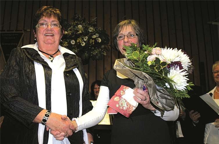 Die Vorsitzende des Gesangvereins Greimersburg, Rita Junge (links) überreicht beim letzten Konzert des Eifelchores der scheidenden Dirigentin Monika Gande einen dicken Blumenstrauß als kleines Dankeschön für ihre jahrelangen Verdienste.