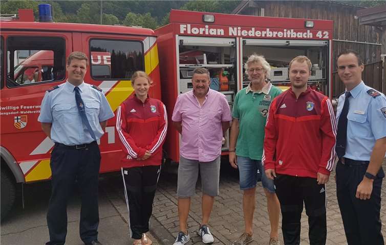 Die Vorsitzenden des Verkehrsvereins Niederbreitbach übergeben feierlich die Trainingsanzüge an die Freiwillige Feuerwehr Niederbreitbach.Fotos: Julien Kolling