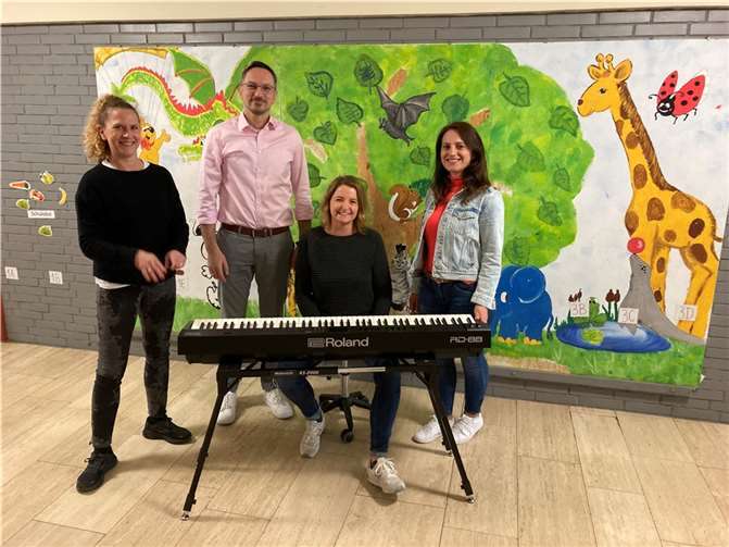 Die Vorstands-Mitglieder des Fördervereins Merita Krasniqi (re.) und Dr. Branislav Poletanovic (2. v. li.) bei der Übergabe des neuen Stage-Pianos an die Schulleitung (Jana Hrabowski (re) und Julia Jockel (sitzend). Quelle: Förderverein