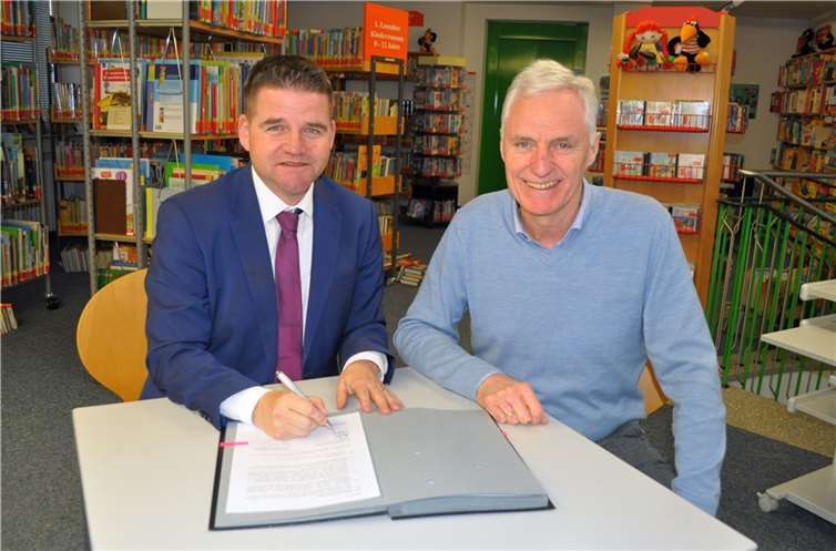 Die beiden Bürgermeister Holger Jung und Dr. Rolf Schumacher (von links) besiegeln mit der Unterzeichnung des Büchereivertrags die interkommunale Zusammenarbeit zwischen Meckenheim und Alfter. Foto: Stadt Meckenheim