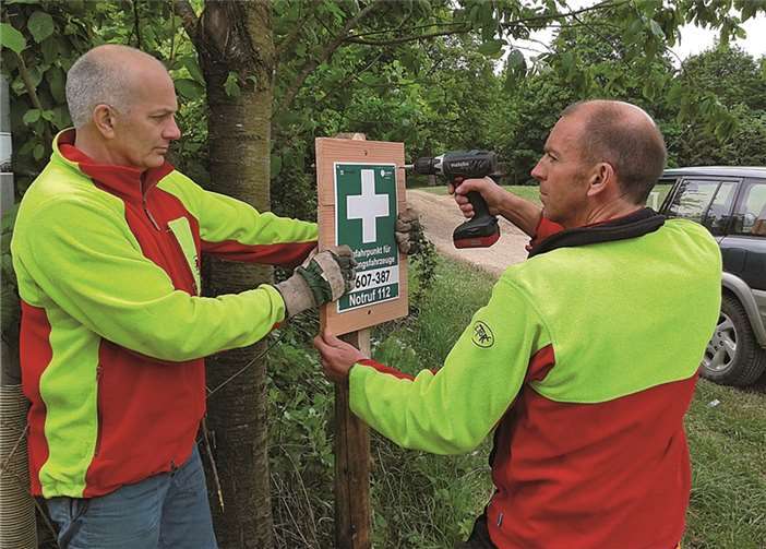 Die beiden kommunalen Forstwirte Georg Linnerz (l.) und Werner Sonntag stellen an der Nordschleife im Adenauer Forst ein neues Rettungsschild auf. Dietmar Ebi / Landesforsten RLP