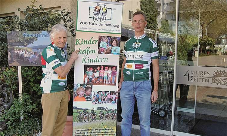 Die ehrenamtlich tätigen Organisatoren Wolfgang Schmidgen und Udo Heuser mit Promotion - Plakat für die „Vor - Tour der Hoffnung“ vor dem Rheinhotel „Vier Jahreszeiten“. Sie werben für den Besuch des Benefiz-Konzertes der „Mainzer Hofsänger, das am Freitag, dem 17. Juli hier stattfinden wird. -FA-