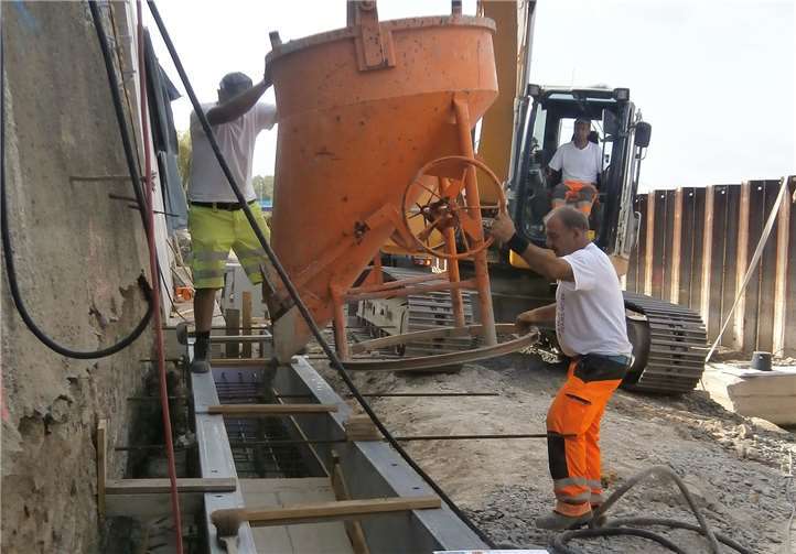 Die fertiggestellte Kaimauerverlängerung und Bauarbeiter, die ein Streifenfundament betonieren. Dort wird später längs der Kaimauer ein Zahnbalken aufgelegt. privat
