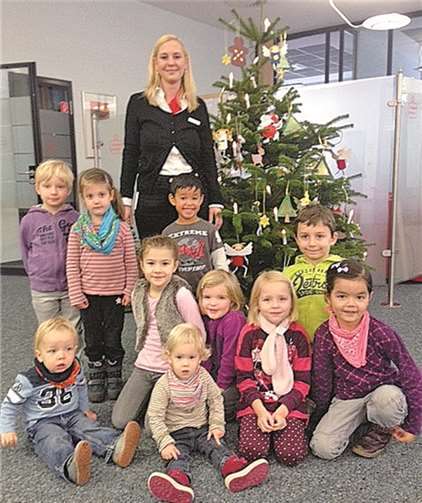 Die fleißigen Helfer der Kindertagesstätte Spatzennest mit Kundenberaterin Tanja Ehmer vor dem fertig geschmückten Weihnachtsbaum in der Filiale der Kreissparkasse Ahrweiler (KSK) in Sinzig. KSK