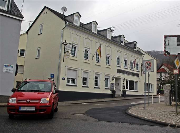 Die frühere Problematik ist auf einen Blick erkennbar: der dunkler geteerte Bereich (rechts) steht nach der Aufweitung mehr zur Verfügung, das Abbiegen oder Einfahren ist nun auch bei Gegenverkehr möglich. Im Hintergrund die Stele aus der ehemaligen Brunnenmitte. Der frühere offene Wasserlauf ist nicht mehr vorhanden.Willi Willig