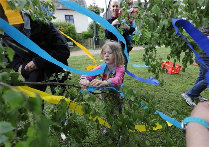 Die fünfjährige Carina bringt hochkonzentriert bunte Bänder an.