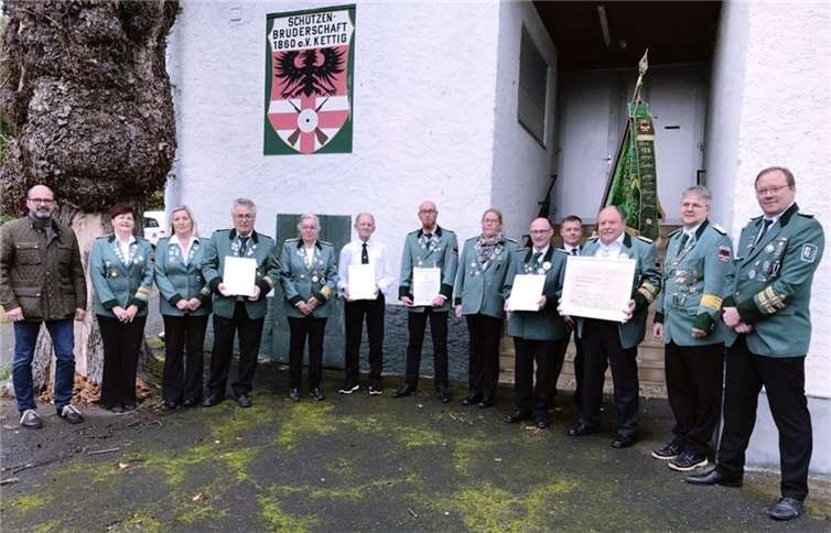 Die geehrten und ausgezeichneten Vereinsmitglieder mit Ortsbürgermeister Peter Moskopp (li.) sowie dem stv. Bezirksbundesmeister Björn Britz (re.), dem neuen ersten Brudermeister Mike Otto (2.v.re.) und Bezirksjungschützenmeisterin Tanja Häring-Otto (6.v.re).Quelle: Schützenbruderschaft Kettig