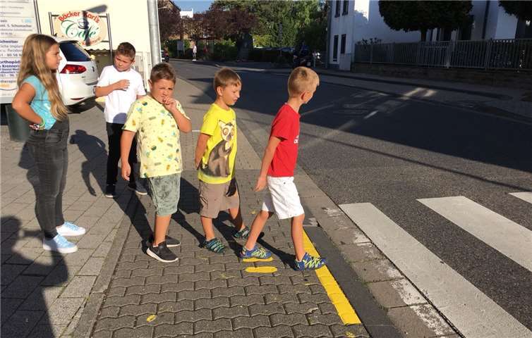 Die gelben Füße und der durchgezogene Strich zeigen an, dass die Kinder stehenbleiben müssen und nach links und rechts schauen sollen.