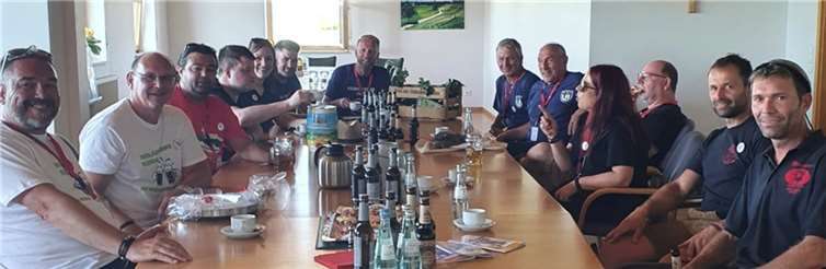 Die gesamte Orga-Familie beim offiziellen Empfang am Freitagabend. Die Eifel hat das Wort: Rieden-Eifel-Ortsbürgermeister Andreas Doll (4. von rechts, zwischen Rieden-Dasing und Rieden-Kaufbeuren) lauscht den Worten von TV Rieden-Vertreterin Daniela Kranz. Auf der linken Seite befinden sich die Abordnungen aus Rosengarten, der Schweiz, Günzburg und Würzburg. Die „Neuen“ im Bunde, Rieden-Forggensee, kamen erst am Samstag dazu.