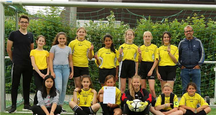 Die jüngsten Fußballerinnen des Are-Gymnasiums und ihre betreuender Lehrer Peter Claßen (re.) zeigen stolz ihre Medaillen, die sie für den dritten Platz im Landesfinale „Jugend trainiert für Olympia“ erhalten haben. Foto: privat