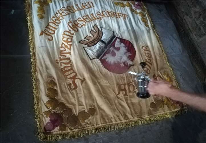 Ein Licht in der Düsternis Die lädierte Fahne der Junggesellen-Schützen wird mit Alkohol konserviert.