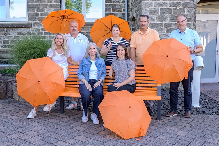 Die orangene Bank vor dem Rathaus der VG Wirges mit allen Projektbeteiligten; v.l.n.r. auf der Bank sitzend: Alexandra Hess, Malerwerkstatt Hess; Bianca Westphal, Gleichstellungsbeauftragte Westerwaldkreis; Jennifer Kothe, Gleichstellungsbeauftragte der Verbandsgemeindeverwaltung Wirges; v.l.n.r. stehend: Andreas Hess, Malerwerkstatt Hess; Alexandra Marzi, Bürgermeisterin VG Wirges; Besim Lulaj, Hausmeister Verbandsgemeindeverwaltung Wirges; Harald Orthey, MdB.