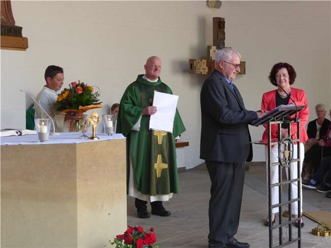 Die scheidende Pfarrsekretärin Mathilde Saxler (von rechts) hört den Dankesworten von Karl-Heinz Gilles zu. Daneben steht Dekan Michael Wilhelm mit dem Messdiener Noah Lescher, der den Blumenstrauß für seine Oma Mathilde hält. Foto: Matthias Schnitzler
