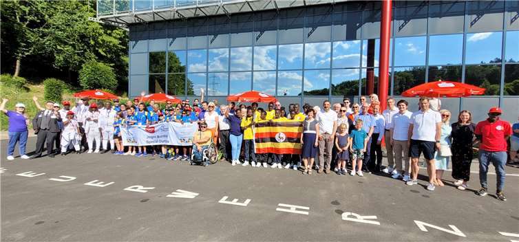 Die stellvertretende Landrätin des Rhein-Sieg-Kreises, Notburga Kunert (vorne, rechts an der Flagge Ugandas stehend), mit den Delegationen sowie den Besucherinnen und Besuchern des Sportfestes.