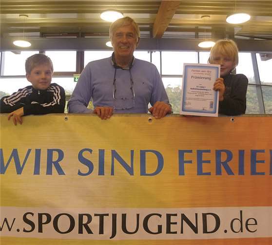 Dieter Prax gemeinsam mit seinen zwei jungen Schützlingen und der Auszeichnung für die Unkeler Ferienfreizeit.privat