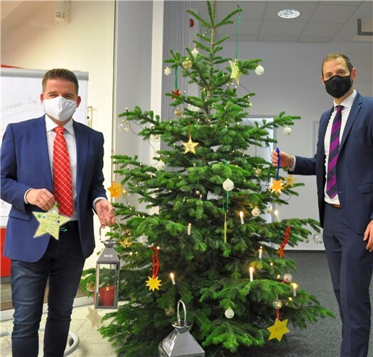 Direkt im Eingangsbereich der Kreissparkasse in der Meckenheimer Altstadt erstrahlt der Weihnachtsbaum, von dem Bürgermeister Holger Jung (links) im Beisein des KSK-Regionaldirektors Sebastian Greven einen Wunsch-Stern abnahm.Foto: Stadt Meckenheim