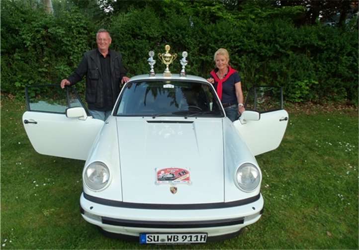 Dorothee und Walter Butter mit ihrem Siegerauto, einem Porsche 911 und den gewonnenen Pokalen.privat