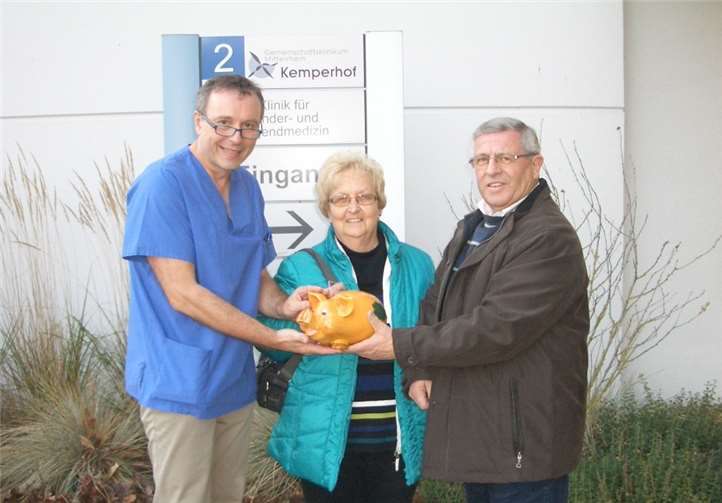 Dr. Hoppe (l.) vom Kemperhof in Koblenz freute sich bei der Spendeübergabe über das prall gefüllte Schweinchen, das Hermann und Elisabeth Barz mitgebracht hatten. Privat