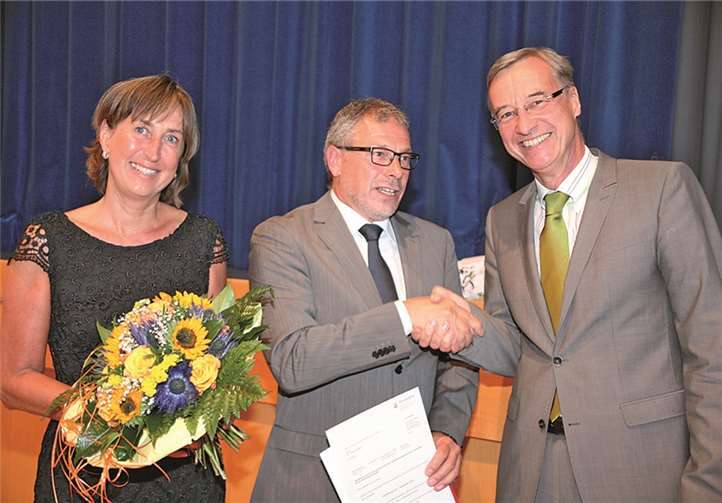 Dr. Johannes Noll (M.) erhält im Beisein von Ehefrau Jutta seine Ernennungsurkunde von Staatssekretär Dr. Thomas Griese.