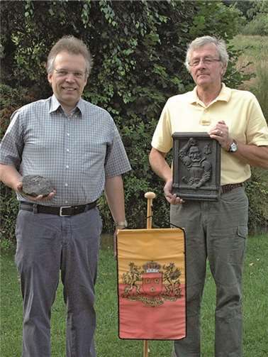 Dr. Volker Reppke (l.) mit Erz und der Vorsitzende Bernd Stratmann mit einer Takenplatte, davor das Wappen der Herzöge von Arenberg. UM