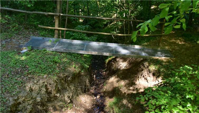 Ehrenamtliche bauten in dem unwegsamen Geländediese Metallbrücke über den kleinen Bach. Fotos: HEP