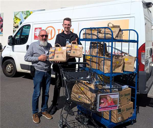 Ein Ehrenamtlicher Helfer der Tafel Polch übernimmt die Spenden, die von einem Mitarbeiter von EDEKA Schütz übergeben wurden.  Foto: Dietmar Barth
