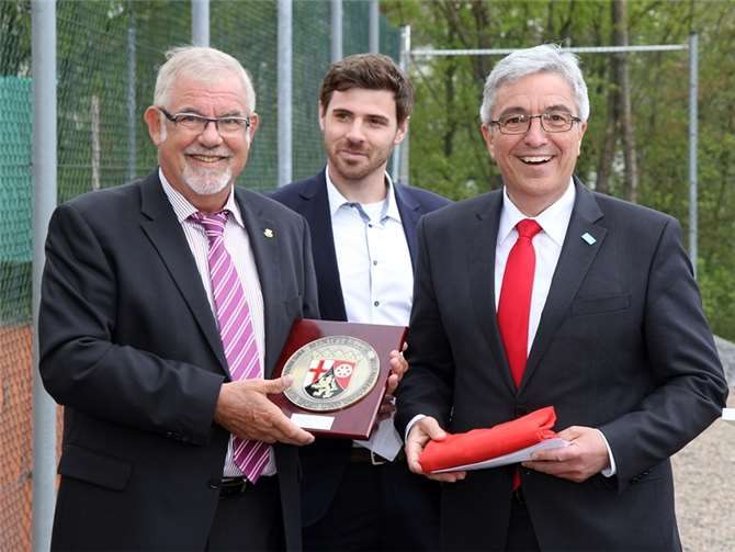 Ein Landeswappen und die Landesfahne zieren künftig das Clubhaus auf der Silberau – einen Zuschuss vom Land gab es schon vorher. Vorsitzender Günter Bröder und Julian Mädrich vom TC Blau-Weiß mit Minister Roger Lewentz.